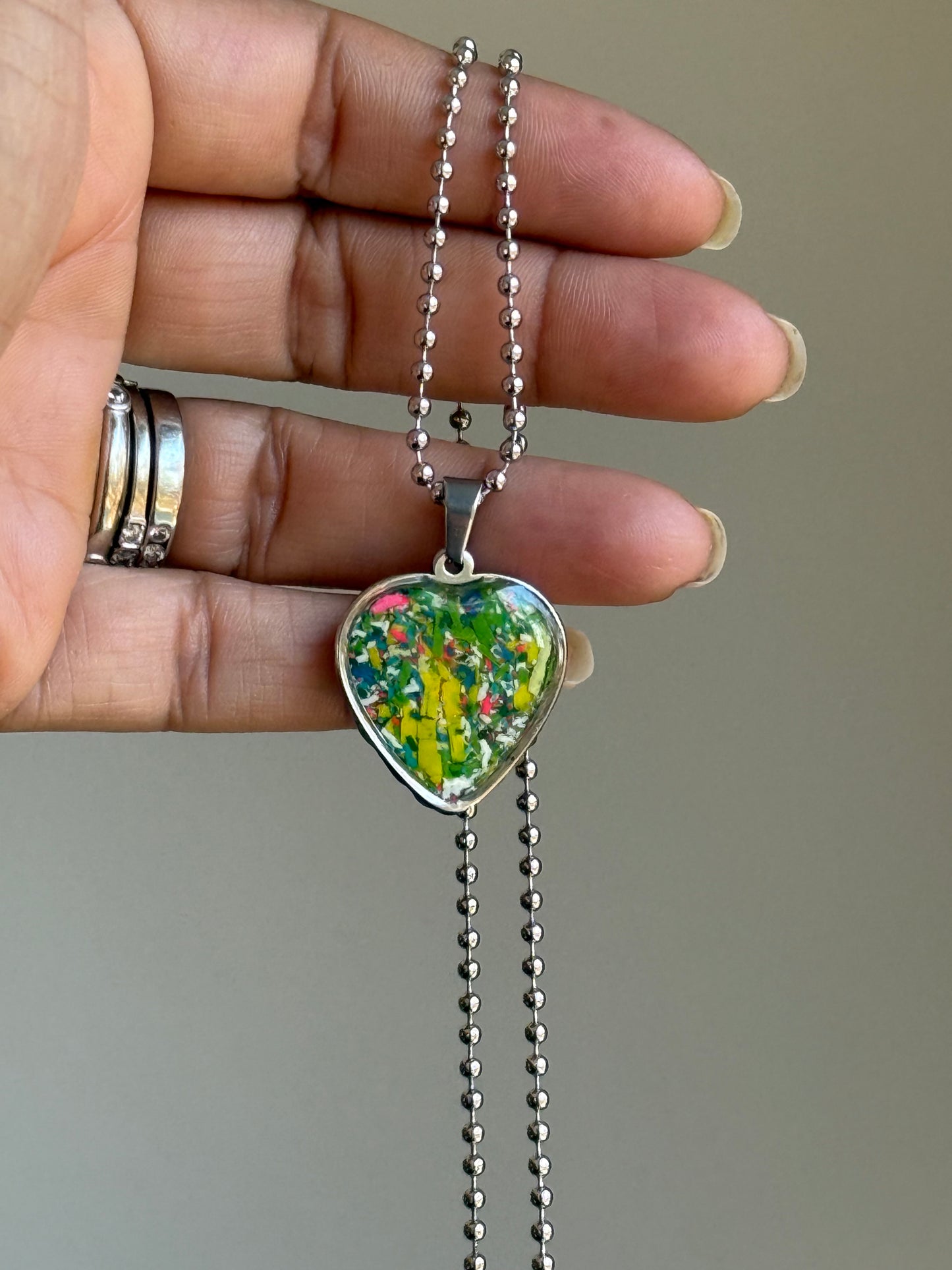 Multicolor crayon filled heart shaped stainless steel pendant. Crayon jewelry by Crayonfetti, mother-daughter based in Atlanta.
