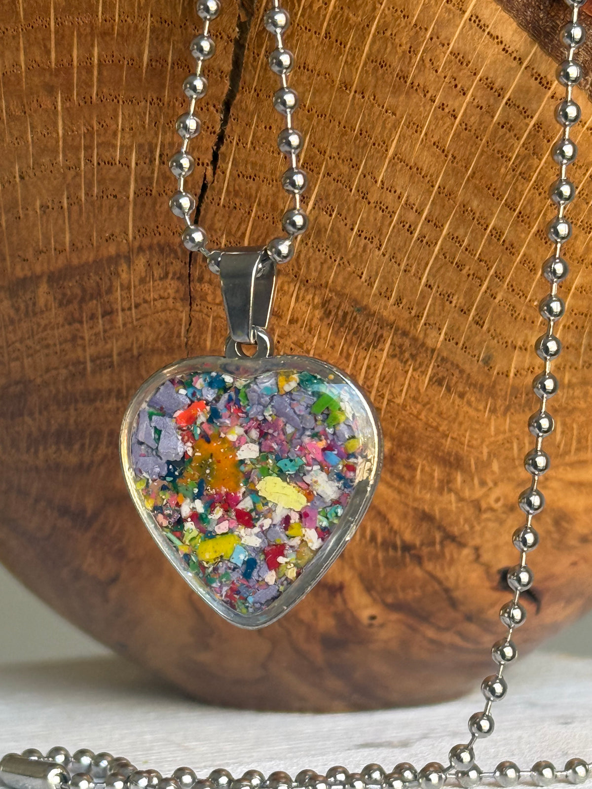 Lilac and soft purple crayon shavings heart necklace, side angle view. Crayon jewelry by Crayonfetti, mother-daughter based in Atlanta