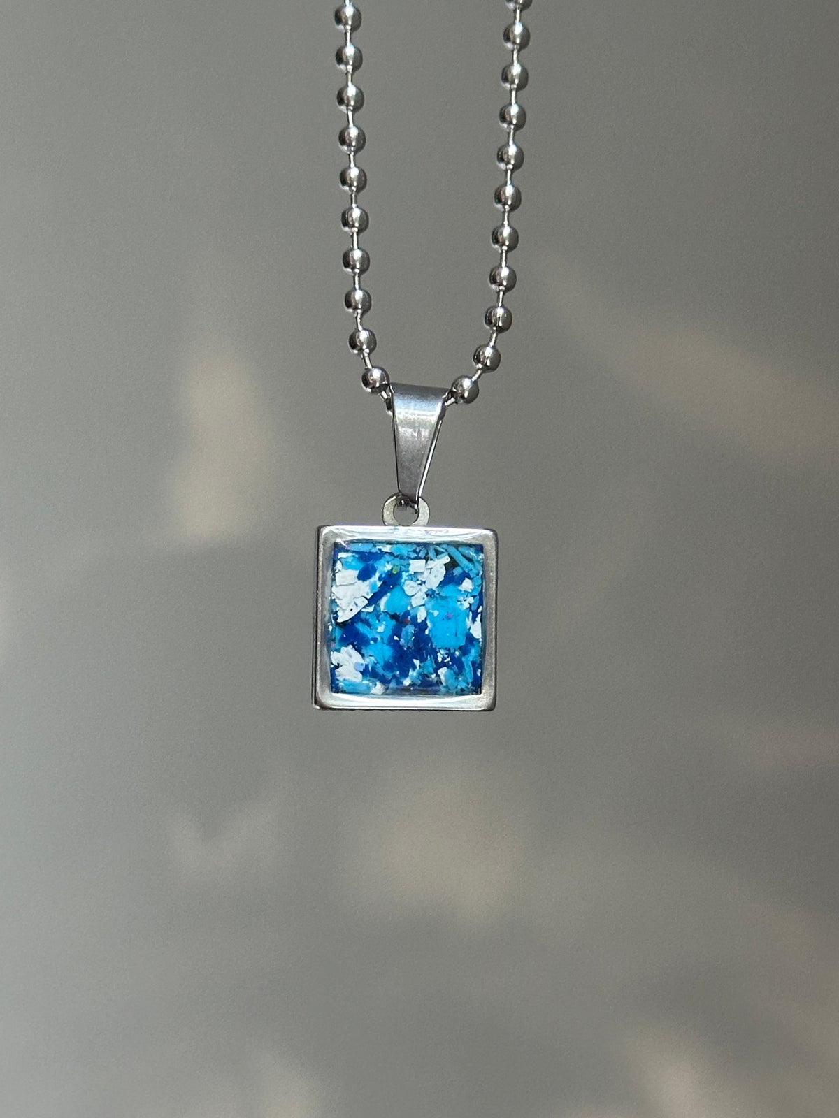 blue and white small square stainless steel pendant filled with crayon shavings. Dainty necklace. Crayonfetti crayon jewelry by mother-daughter based in Atlanta, Georgia.