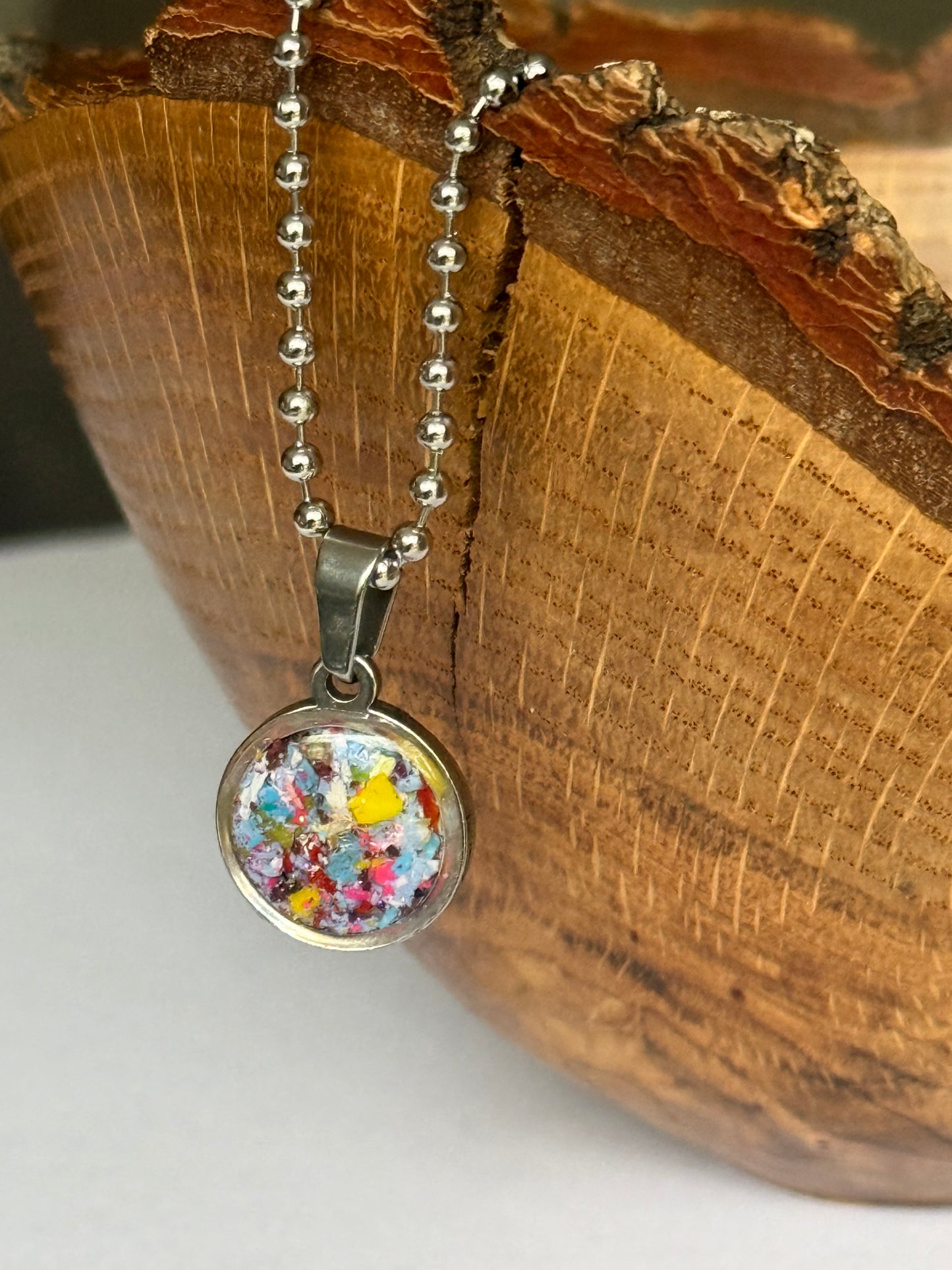 Blue, teal, and yellow round stainless steel pendant filled with crayon shavings. Dainty necklace. Crayonfetti crayon jewelry by mother-daughter based in Atlanta, Georgia.