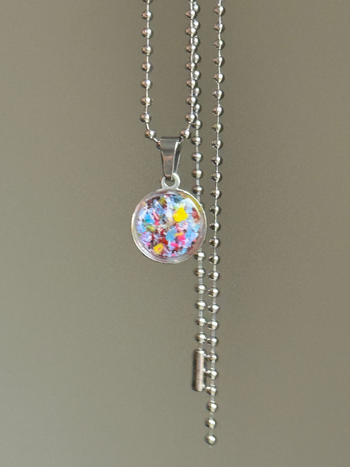 Blue, teal, and yellow round stainless steel pendant filled with crayon shavings. Dainty necklace. Crayonfetti crayon jewelry by mother-daughter based in Atlanta, Georgia.