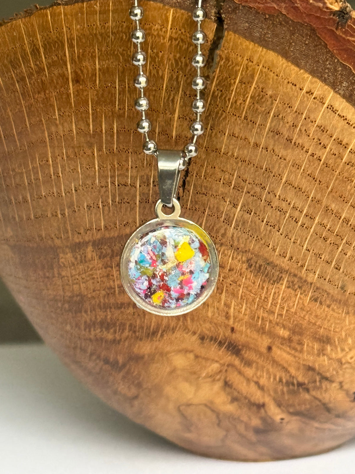 Blue, teal, and yellow round stainless steel pendant filled with crayon shavings. Dainty necklace. Crayonfetti crayon jewelry by mother-daughter based in Atlanta, Georgia.