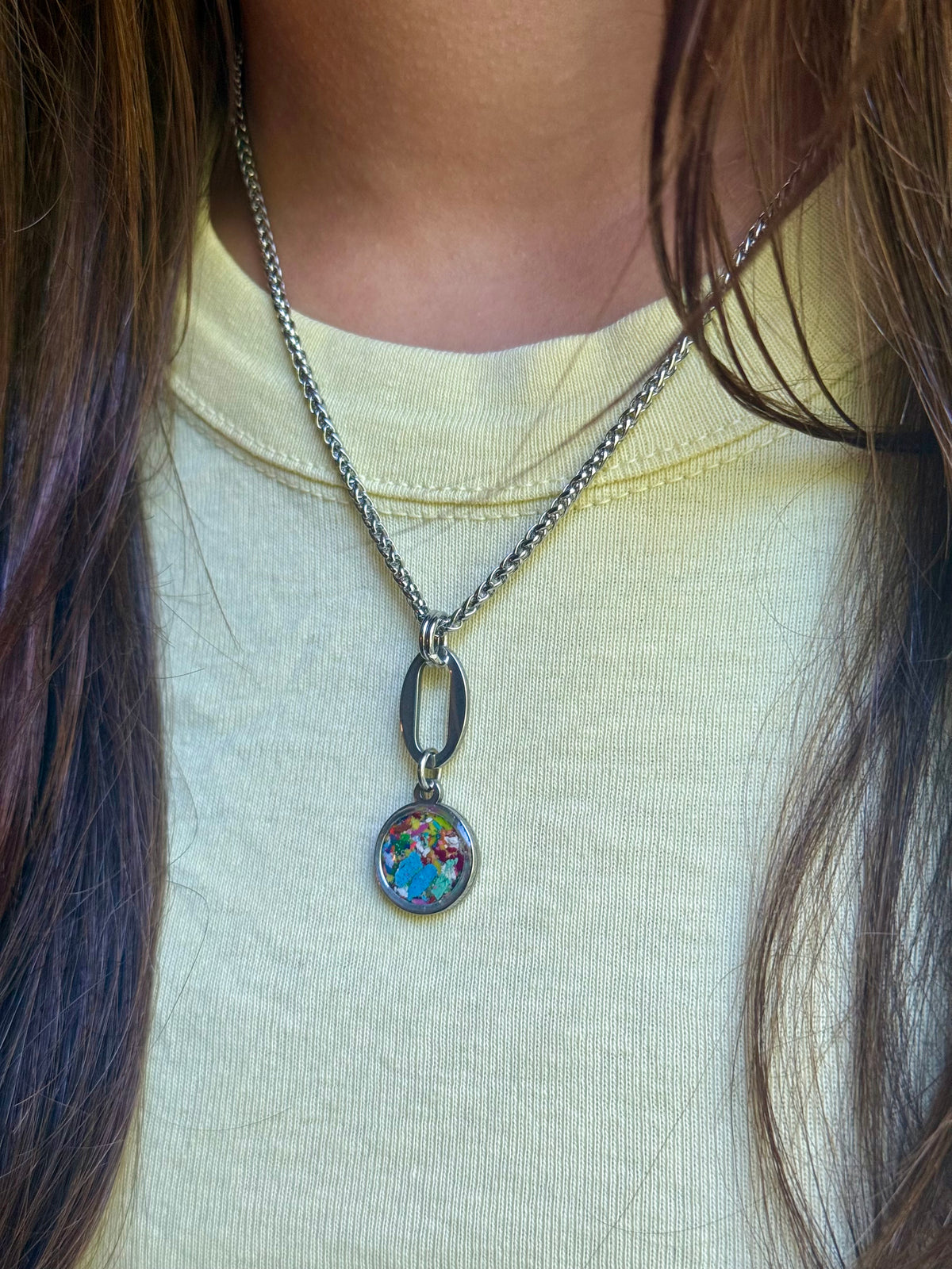 Model showcasing the 12mm Marisol round stainless steel pendant with sky blue resin inlay.