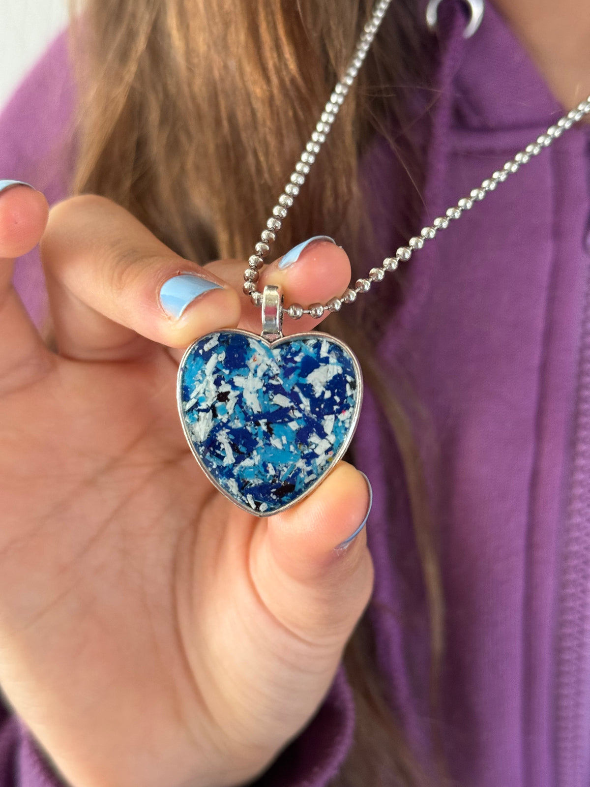 Blue and white crayon filled heart shaped stainless steel pendant. Crayon jewelry by Crayonfetti, mother-daughter based in Atlanta.