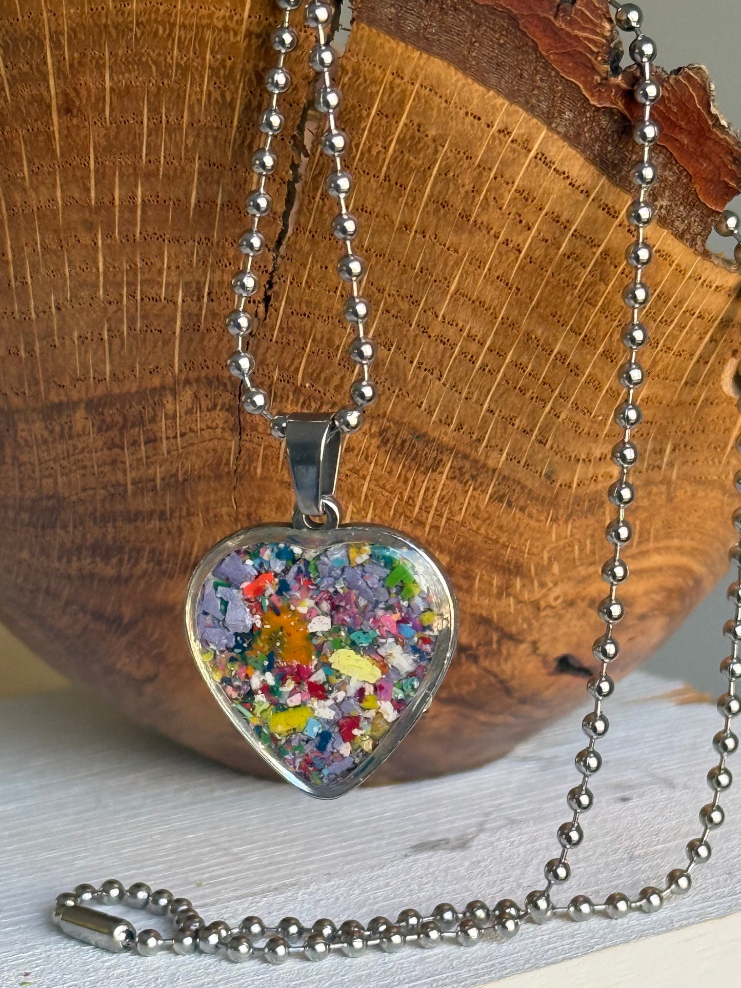 Close-up detail of lilac crayon shavings heart pendant on chain. Crayon jewelry by Crayonfetti, mother-daughter based in Atlanta