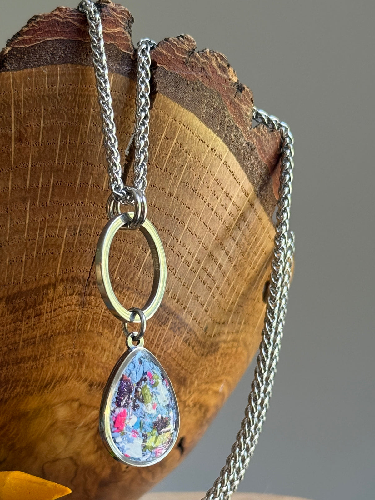 Detailed view of periwinkle and purple crayon fragments suspended over the edge of a textured wooden bowl.