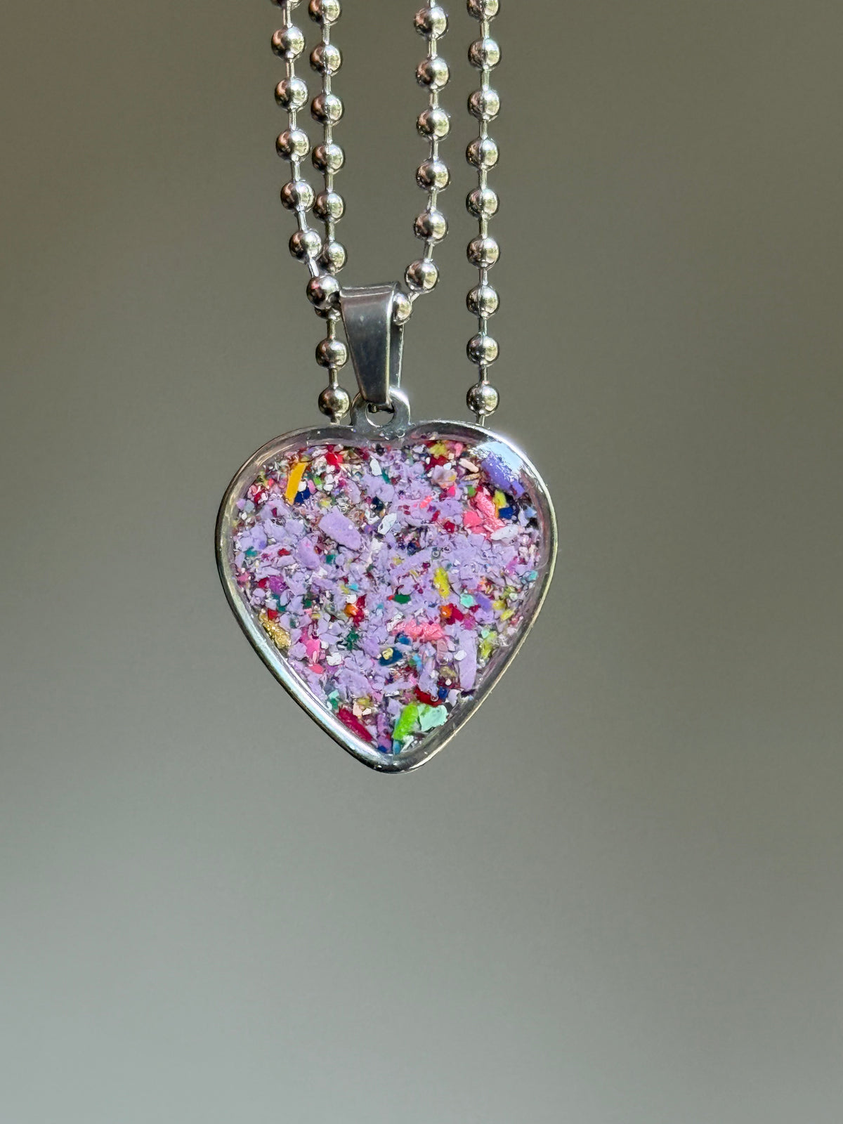 stainless steel heart shaped pendant filled with crayons in purple hues. crayon jewelry by crayonfetti