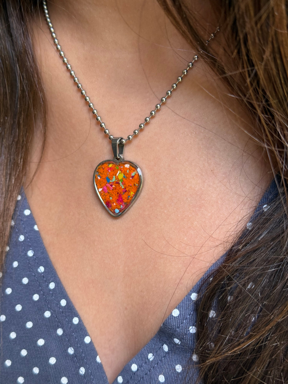 crayon jewelry heart necklace featuring a bold orange base with colorful sprinkle details made from reclaimed crayon shavings.
