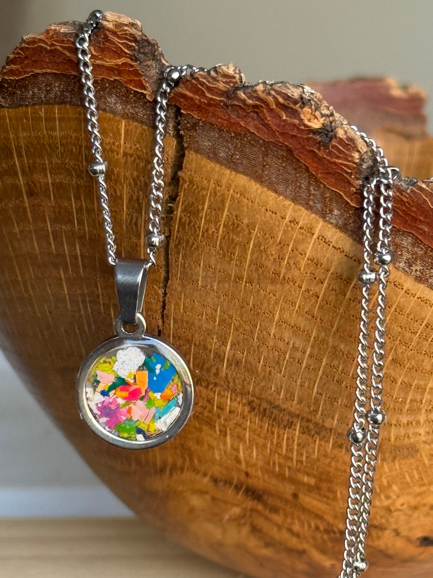 multicolor and vibrant round stainless steel pendant filled with crayon shavings. Dainty necklace. Crayonfetti crayon jewelry by mother-daughter based in Atlanta, Georgia.