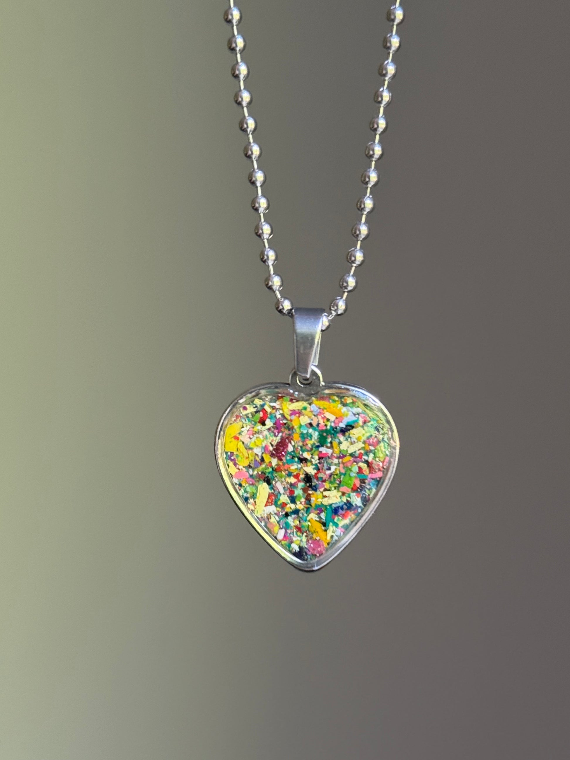 dark-toned crayon shavings heart pendant colorful upcycled necklace. Crayon jewelry by Crayonfetti, mother-daughter based in Atlanta.