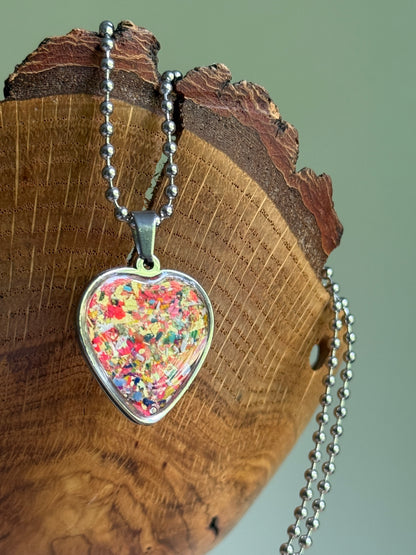 Macro close-up of the Solar Spark heart pendant showing the polished clear resin and crayon texture.