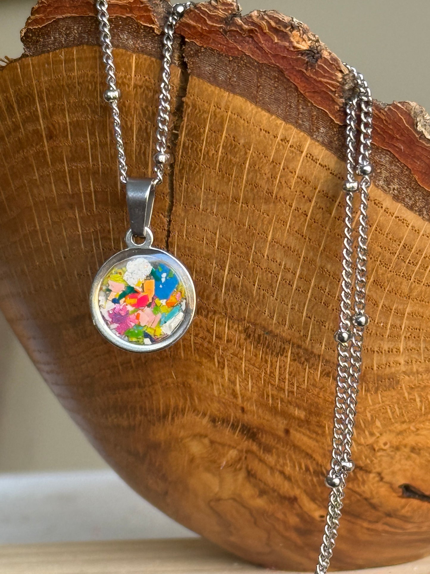 multicolor and vibrant round stainless steel pendant filled with crayon shavings. Dainty necklace. Crayonfetti crayon jewelry by mother-daughter based in Atlanta, Georgia.