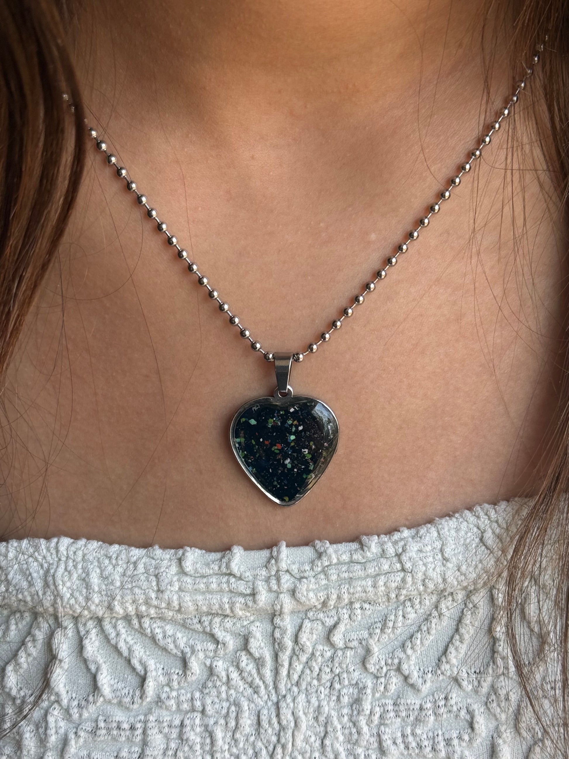 Heart-shaped crayon jewelry pendant with black base crayon base and vibrant colorful sprinkles sealed in clear resin by crayonfetti