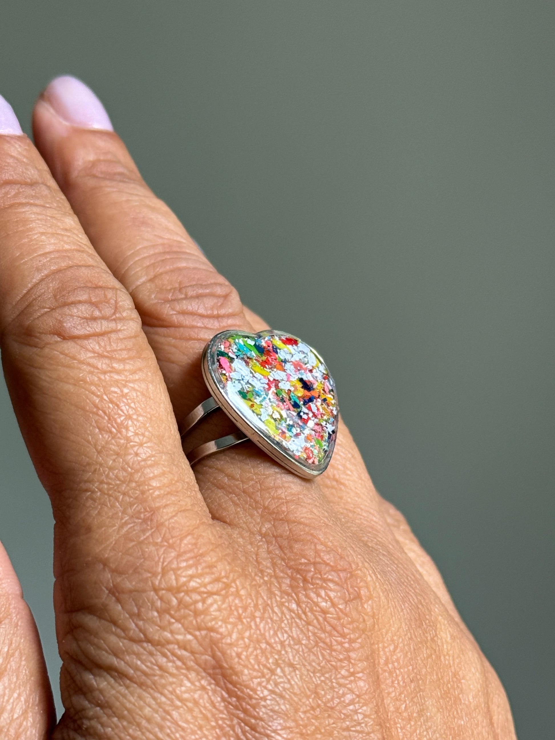 Stainless steel crayon ring with a vibrant blue and multicolored upcycled crayon heart bezel.