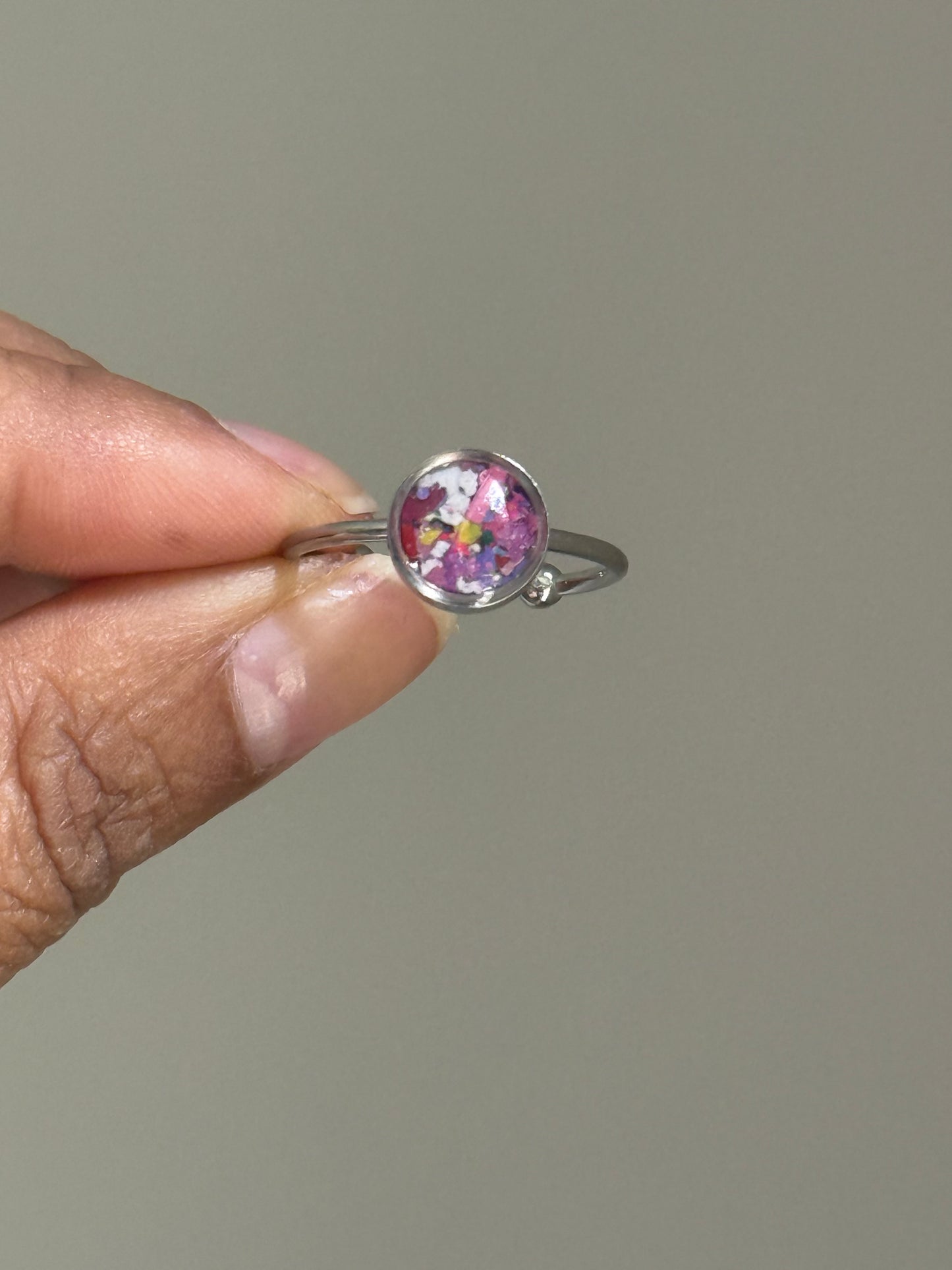 A delicate stainless steel ring featuring a colorful blend of recycled crayon shavings, styled as a dainty stacking ring by Crayonfetti.
