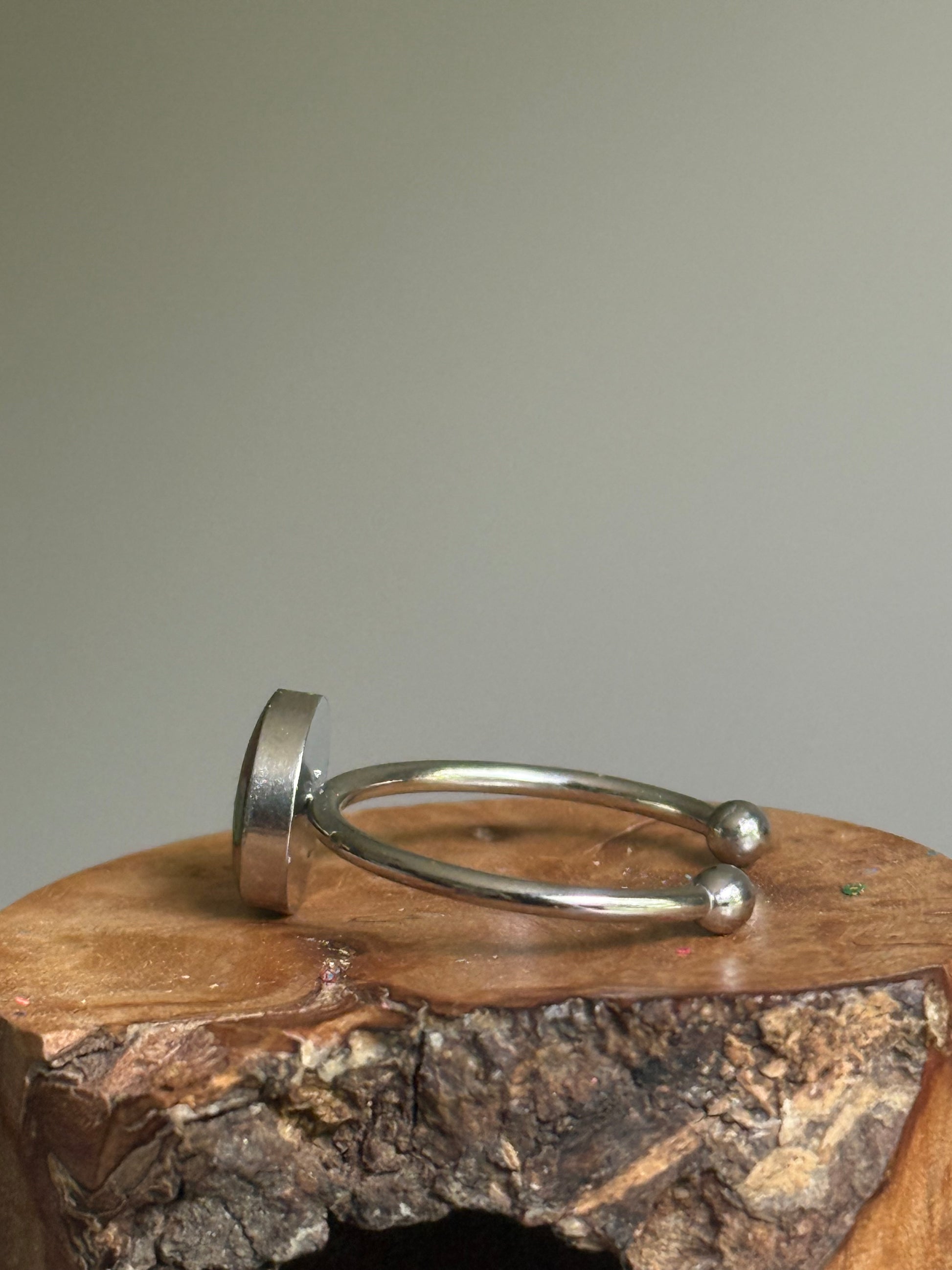 A delicate stainless steel ring filled with a cheerful, sun-kissed blend of recycled orange crayon shavings, handmade by Crayonfetti