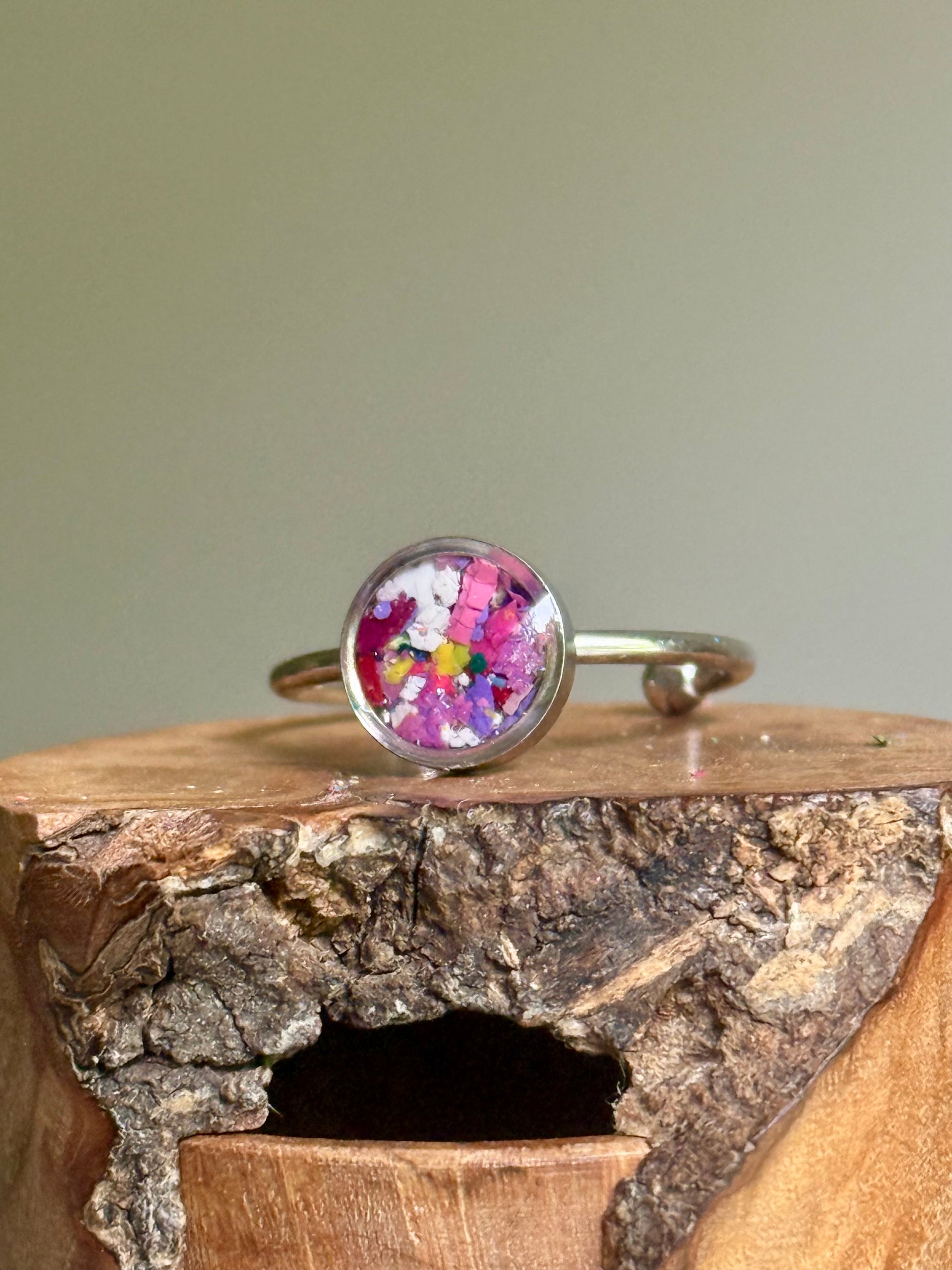 A dainty stainless steel jewelry ring showcasing a hand-placed mix of soft lavender crayon shavings.