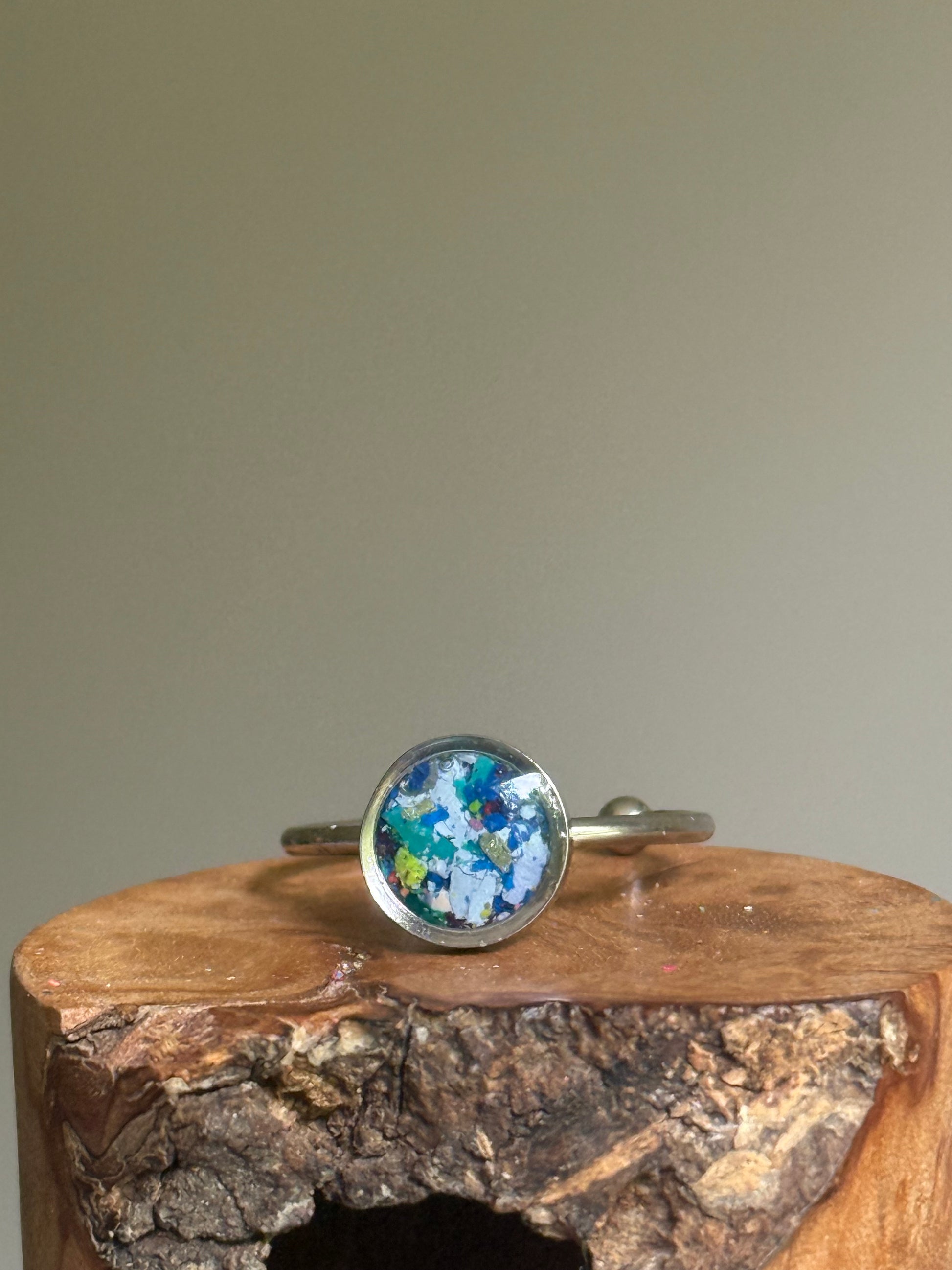 A dainty stainless steel ring featuring a deep, moody mosaic of dark blue and black crayon shavings, created as unique crayon jewelry by Crayonfetti.