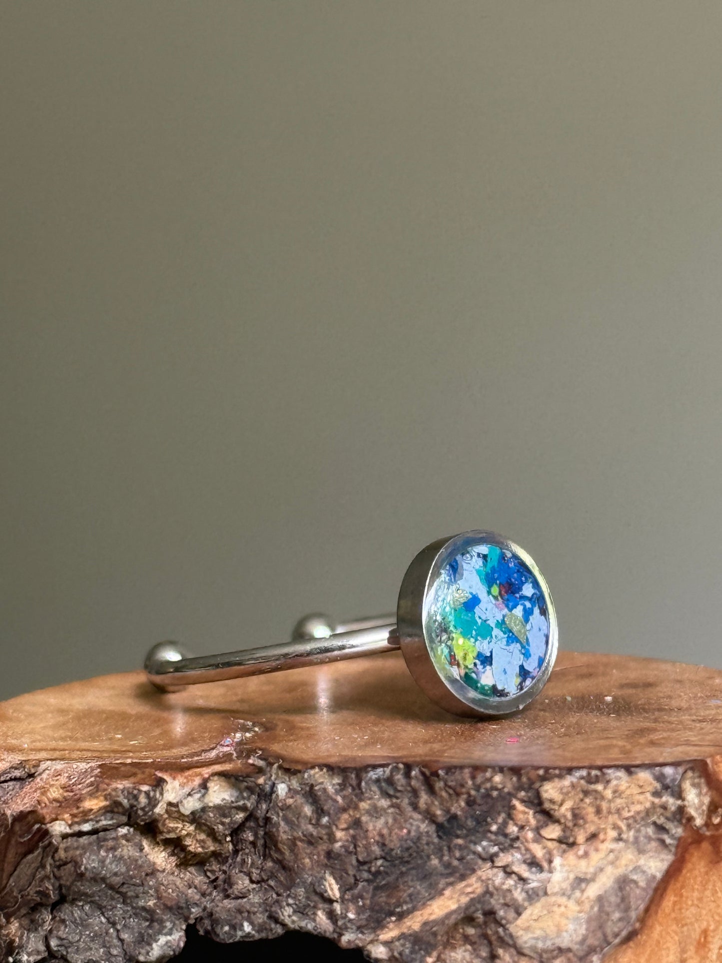Close-up of a minimalist stainless steel ring showcasing a hand-placed, midnight-inspired blend of rich navy crayon shavings.