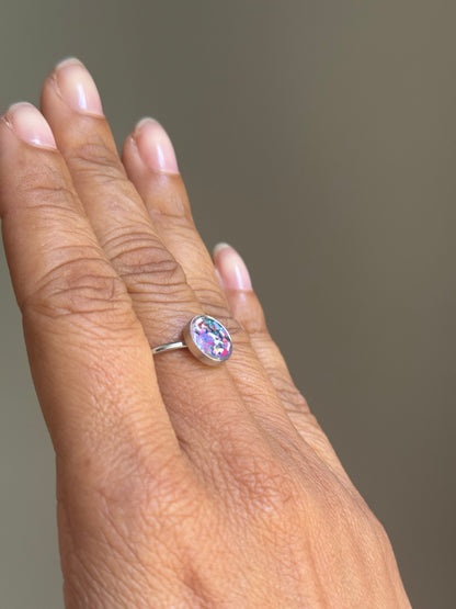 Close-up of a minimalist stainless steel ring showcasing a hand-placed, delicate mosaic of pastel purple crayon shavings.
