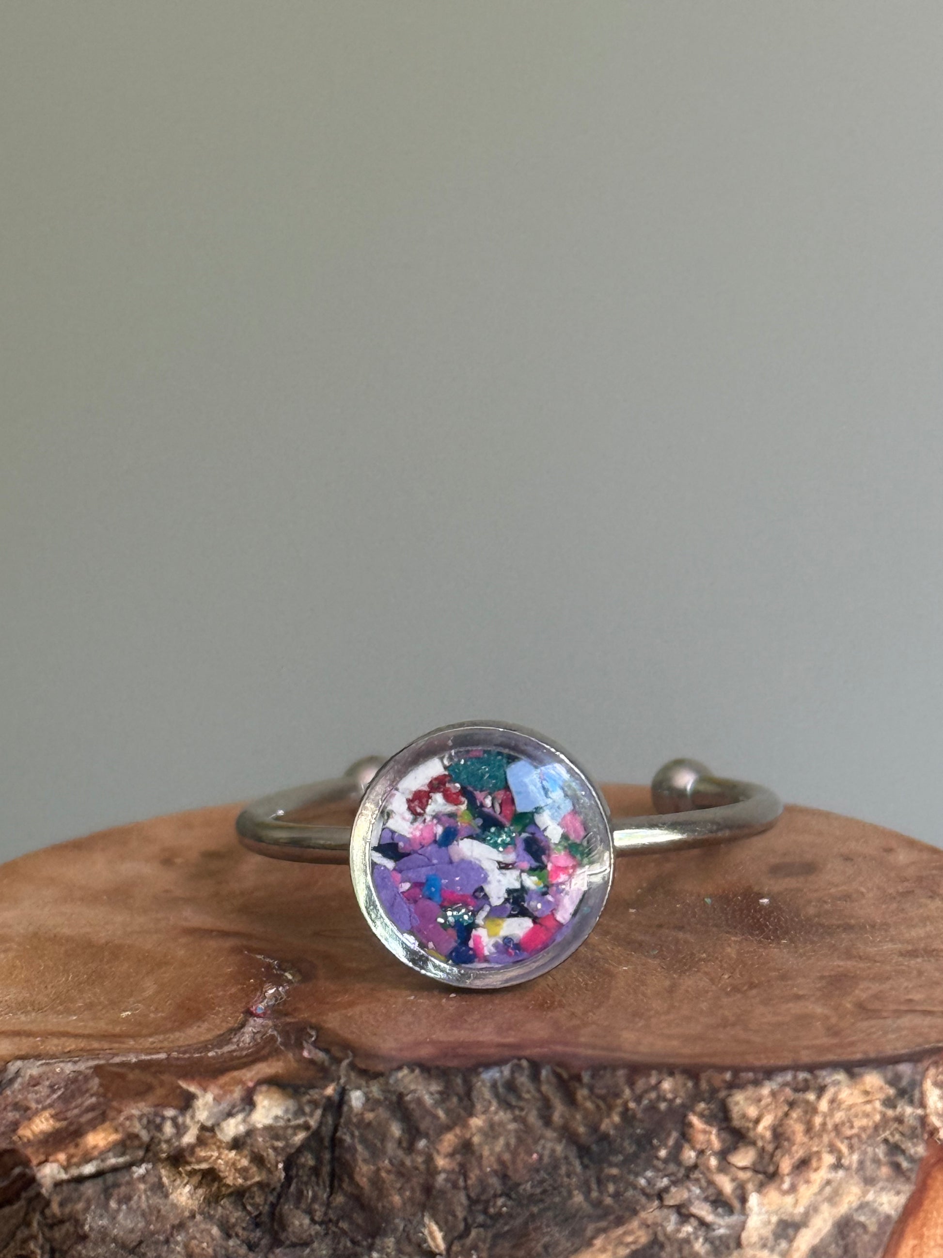 A dainty stainless steel ring featuring a soft, dreamy blend of lavender and violet crayon shavings, created as unique crayon jewelry by Crayonfetti.