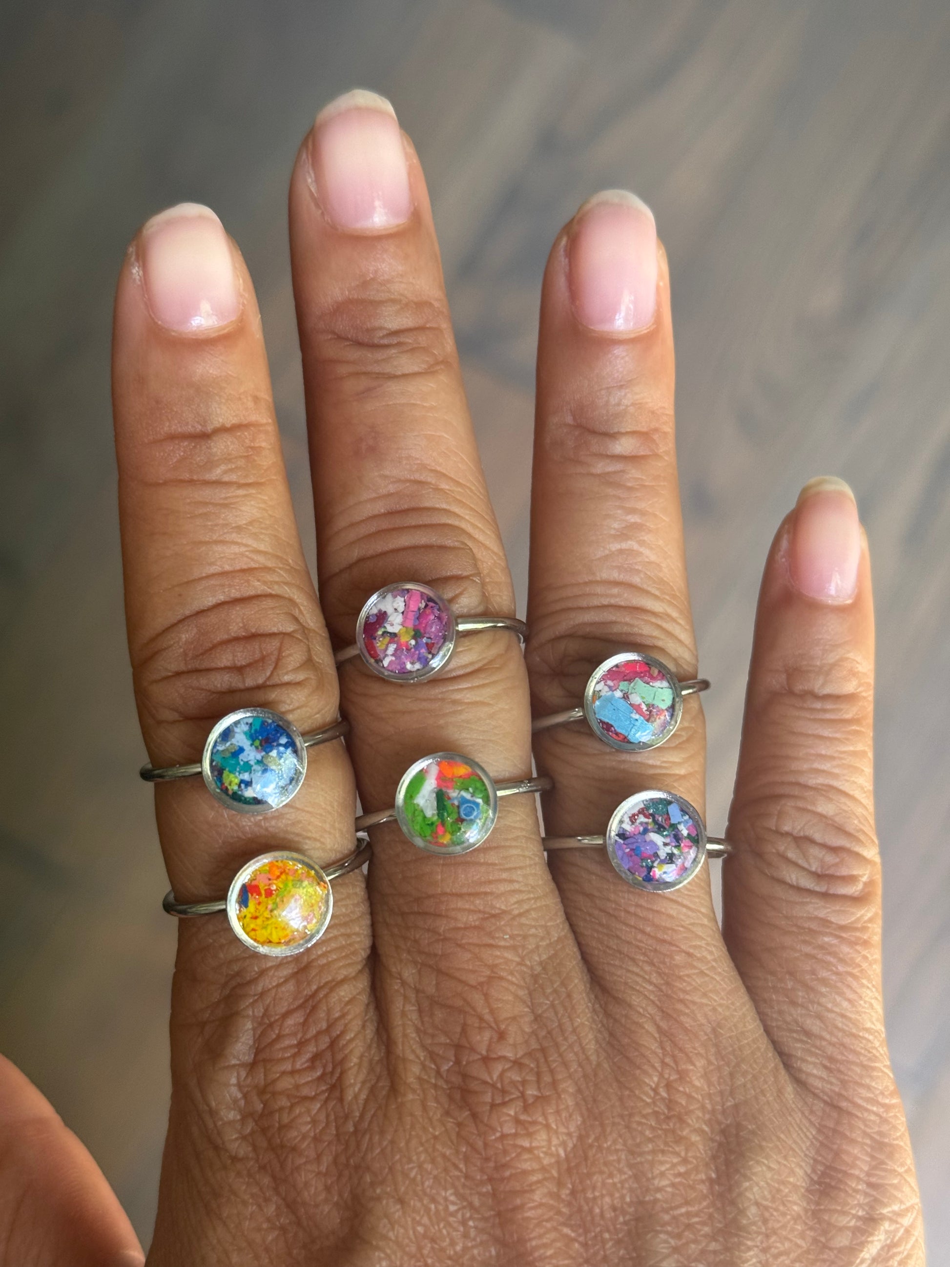 A beautiful collection of dainty stainless steel rings, including the neon orange Sunkist ring, showcased together to display the colorful variety of crayon jewelry by Crayonfetti.
