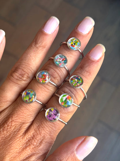 A beautiful collection of dainty stainless steel rings, showcased together to display the colorful variety of crayon jewelry by Crayonfetti.