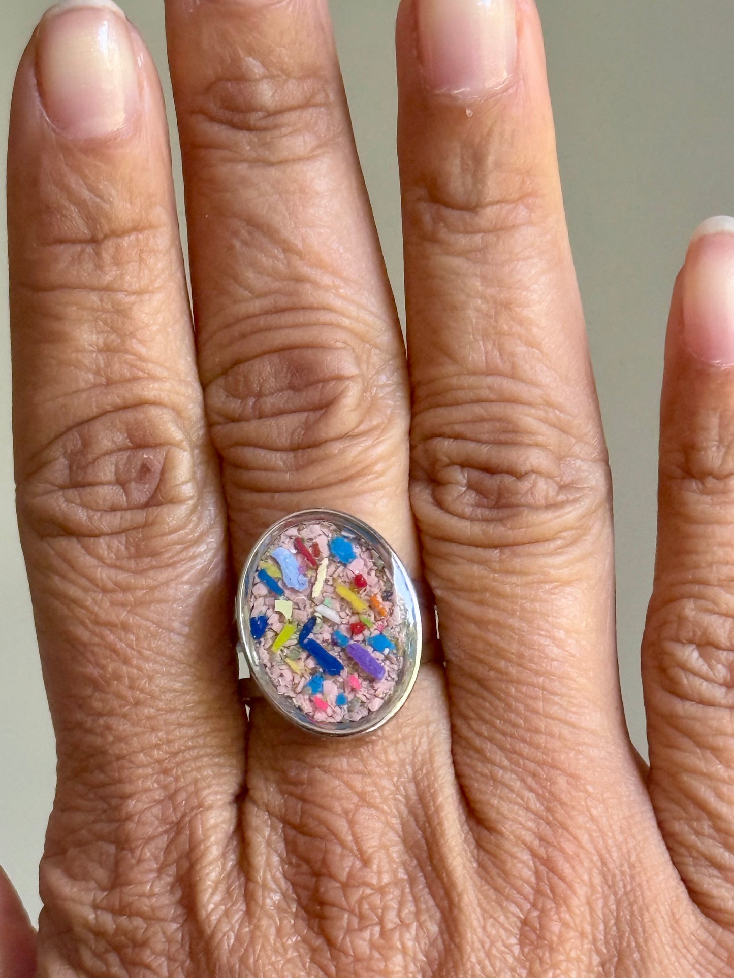 oval ring filled with pink and multicolor crayon shavings.  Crayonfetti crayon jewelry