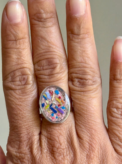 oval ring filled with pink and multicolor crayon shavings.  Crayonfetti crayon jewelry