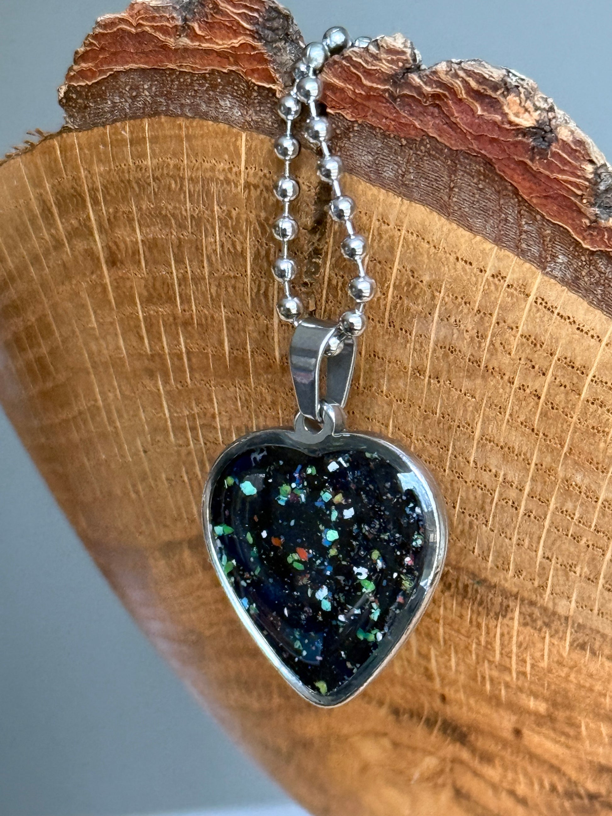Handmade black heart pendant created from reclaimed crayon shavings with colorful freckled details, unique crayon jewelry.
