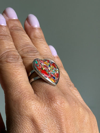 Handcrafted stainless steel crayon ring holding a bright red and multicolor crayon shavings.  It's crayon jewelry. Heart shaped rings. 