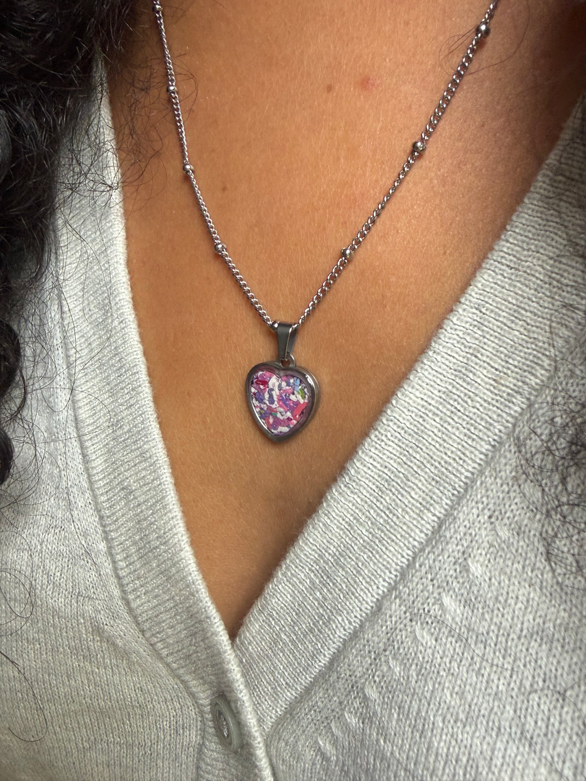 side profile of hypoallergenic stainless steel heart bezel filled with pink and purple upcycled resin art.