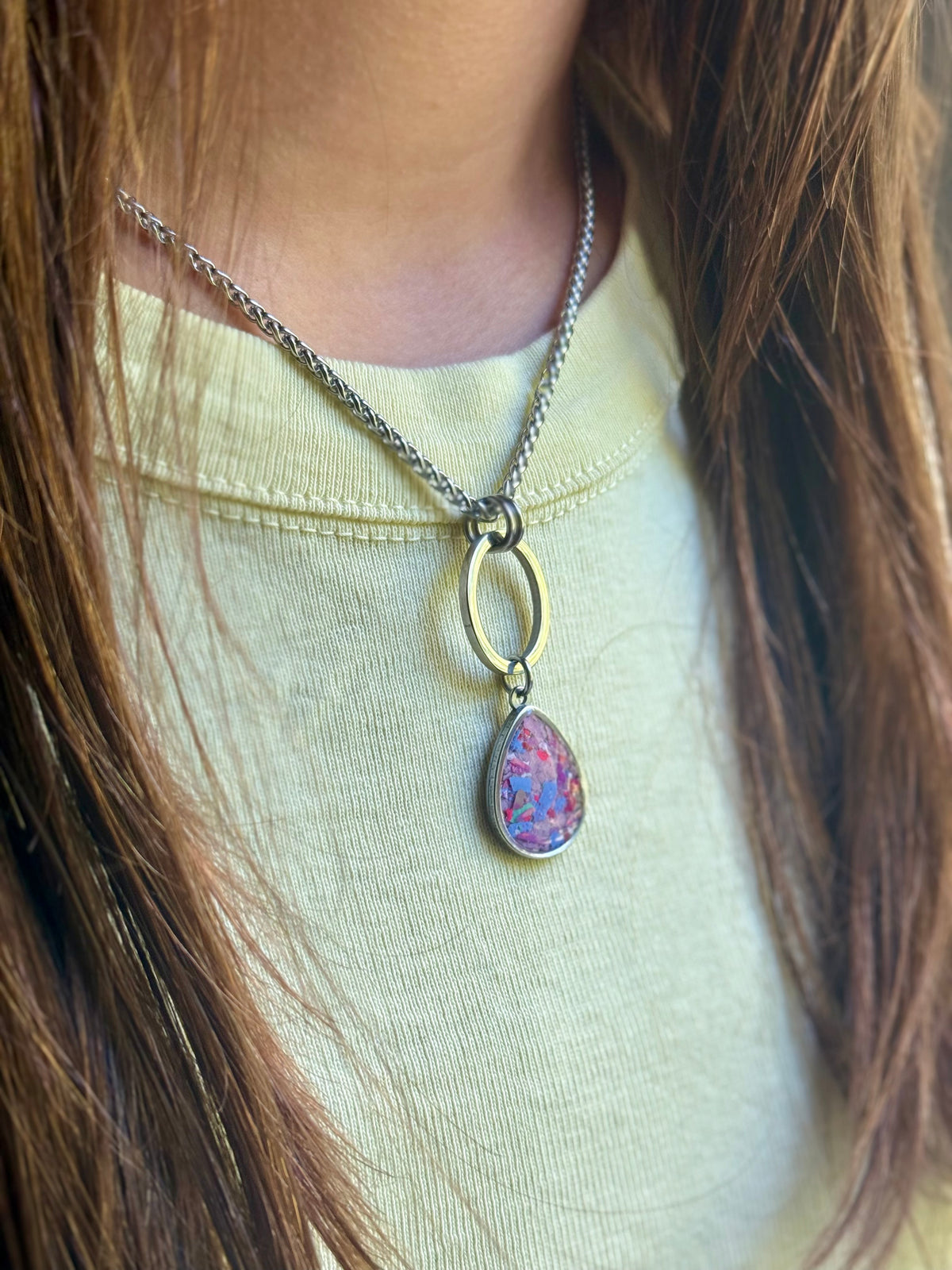 Close-up of model in a yellow top showcasing the Carmen pendant featuring pink and lilac resin inlay. CRAYON JEWELRY