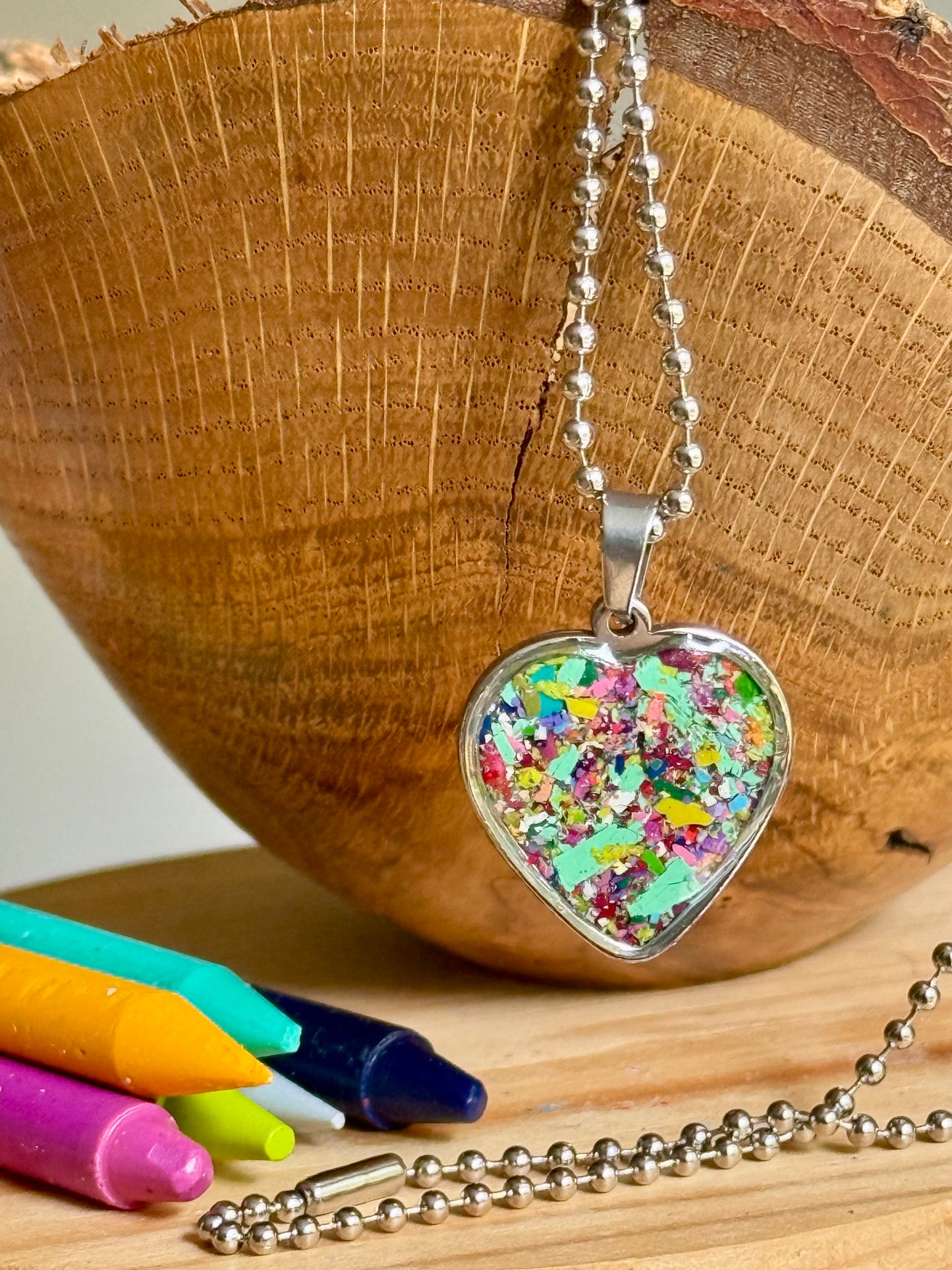 Heart-shaped crayon jewelry necklace featuring vibrant layers of reclaimed crayon shavings