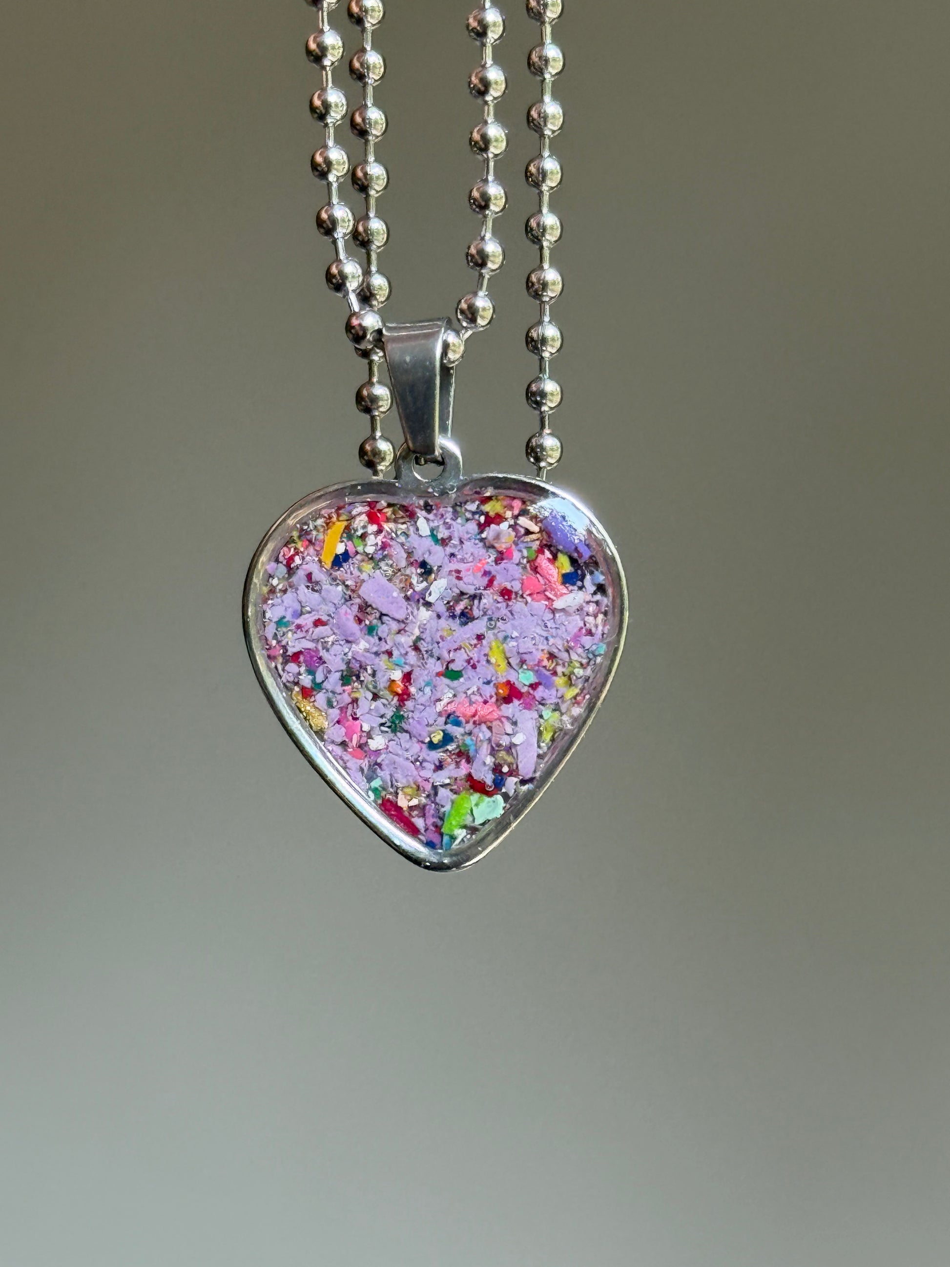 stainless steel heart shaped pendant filled with crayons in purple hues.  crayon jewelry by crayonfetti
