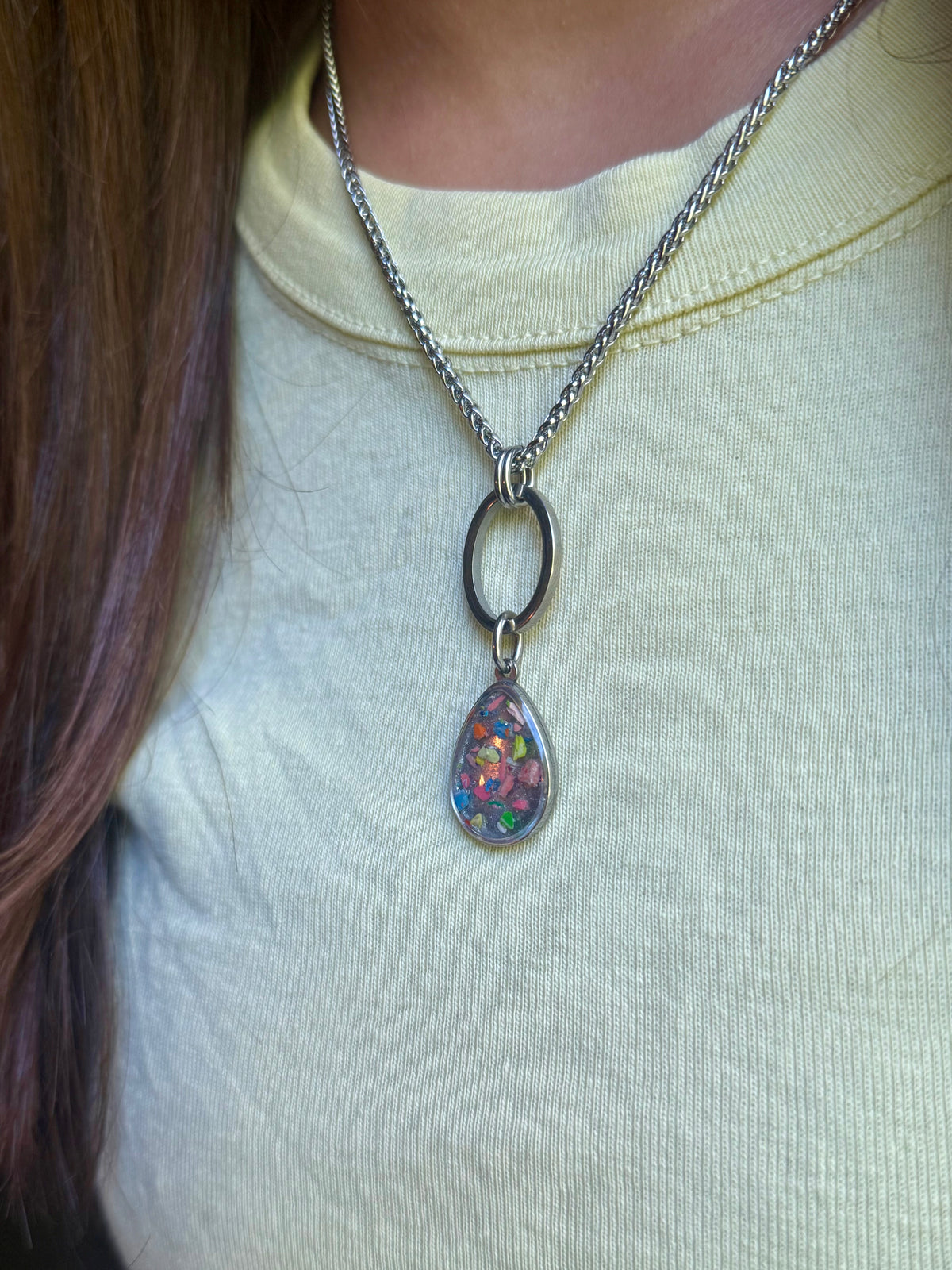 Close-up of model in a yellow top showcasing the stainless steel  geometric open link resin crayon necklace.