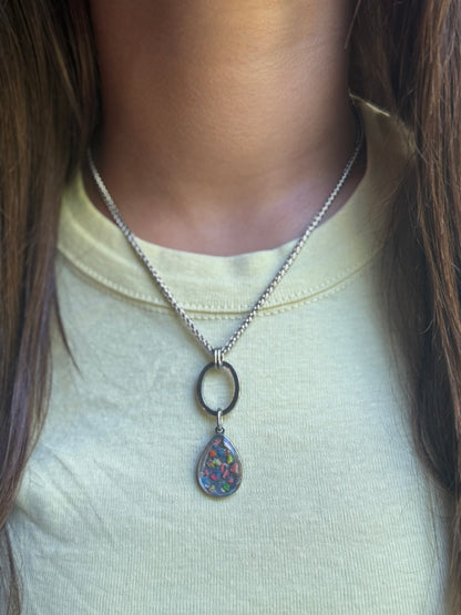Model in a bright yellow top wearing the stainless steel Carmen open oval pendant necklace with a round colorful resin accent